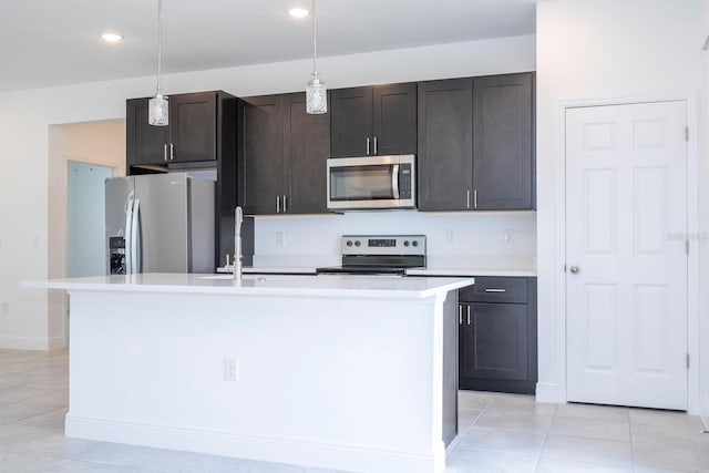 kitchen featuring appliances with stainless steel finishes, dark brown cabinetry, a kitchen island with sink, and decorative light fixtures