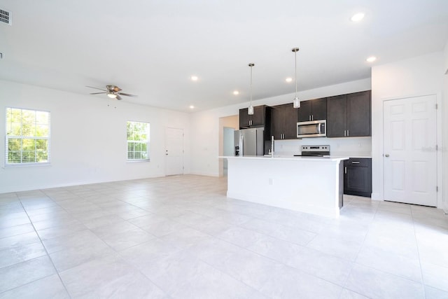 kitchen with a kitchen island with sink, hanging light fixtures, dark brown cabinetry, appliances with stainless steel finishes, and ceiling fan