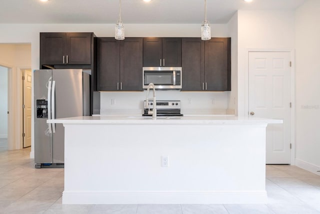 kitchen with appliances with stainless steel finishes, decorative light fixtures, dark brown cabinets, and an island with sink