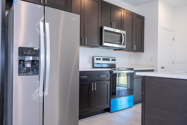 kitchen with dark brown cabinets, light stone counters, stainless steel appliances, and light tile patterned floors