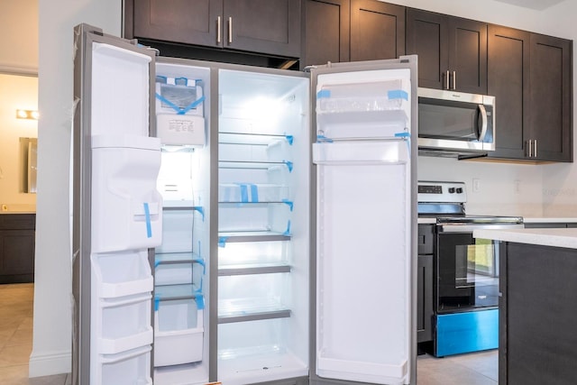 kitchen with appliances with stainless steel finishes, dark brown cabinetry, and light tile patterned flooring