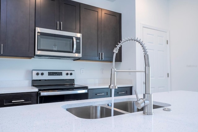 kitchen featuring light stone counters, appliances with stainless steel finishes, sink, and dark brown cabinets