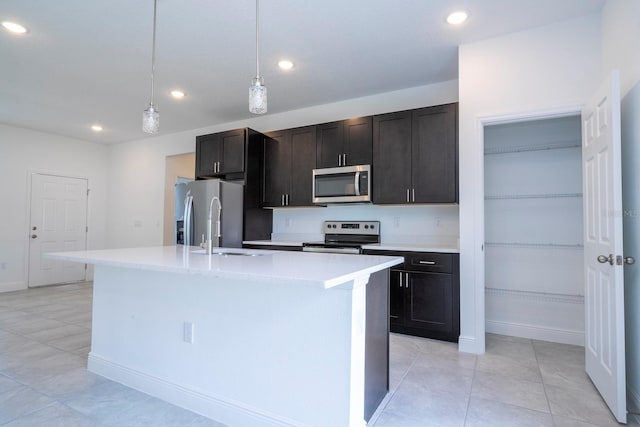 kitchen featuring dark brown cabinetry, decorative light fixtures, a kitchen island with sink, and stainless steel appliances