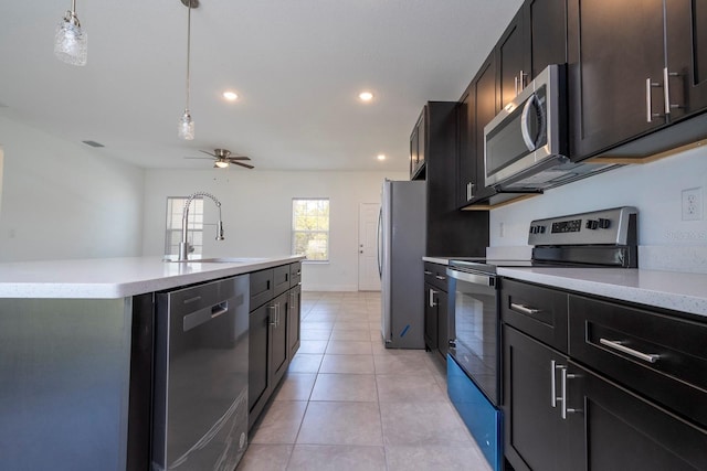 kitchen featuring an island with sink, sink, pendant lighting, appliances with stainless steel finishes, and ceiling fan