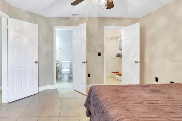 tiled bedroom with connected bathroom, ceiling fan, a closet, and a spacious closet