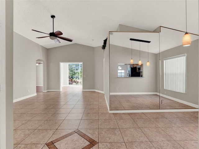 unfurnished room featuring a textured ceiling, lofted ceiling, ceiling fan, and light tile patterned flooring