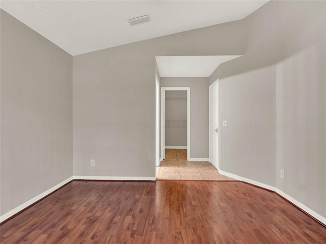 empty room featuring light wood-type flooring and vaulted ceiling