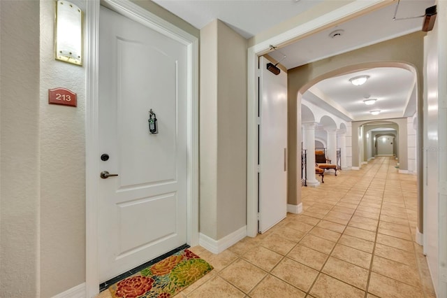 hall with light tile patterned floors and ornate columns