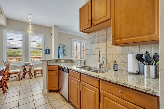 kitchen with stainless steel dishwasher, a wealth of natural light, sink, and light stone counters