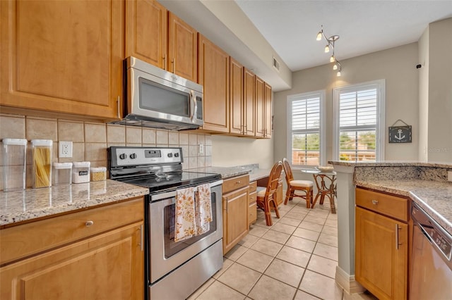 kitchen with light stone countertops, light tile patterned floors, decorative backsplash, and appliances with stainless steel finishes