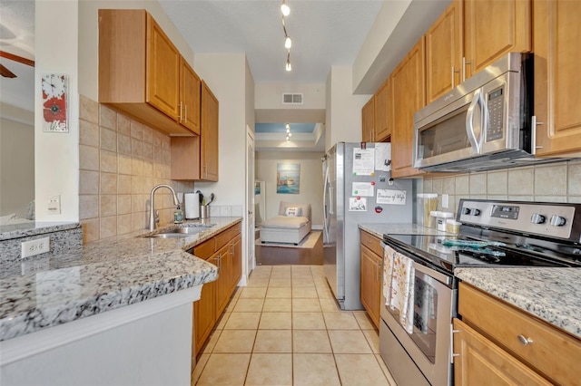 kitchen featuring stainless steel appliances, light tile patterned floors, light stone countertops, decorative backsplash, and sink