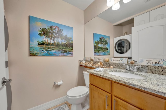 bathroom featuring stacked washing maching and dryer, tile patterned flooring, vanity, and toilet