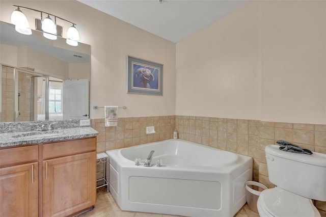 bathroom with tile walls, tile patterned floors, vanity, a tub, and toilet