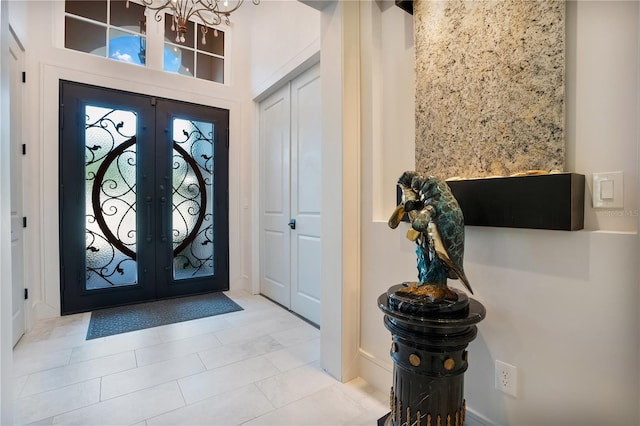 foyer entrance featuring an inviting chandelier, light tile patterned floors, and french doors