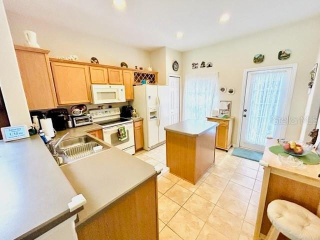 kitchen featuring kitchen peninsula, sink, a center island, light tile patterned floors, and white appliances