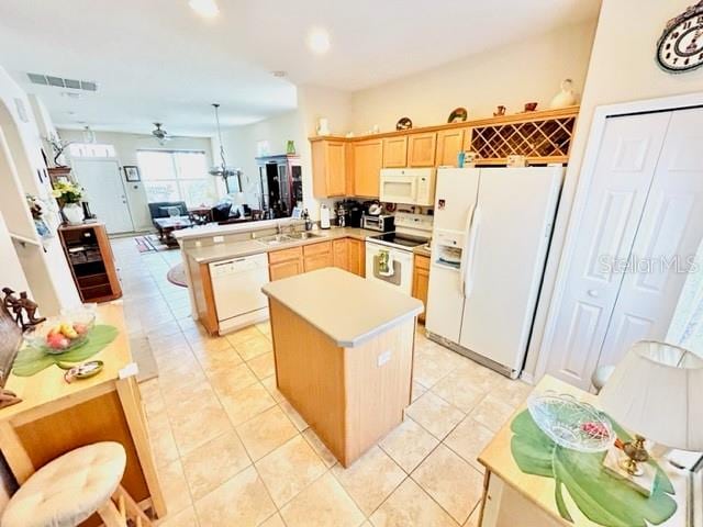 kitchen featuring kitchen peninsula, light tile patterned floors, sink, a center island, and white appliances