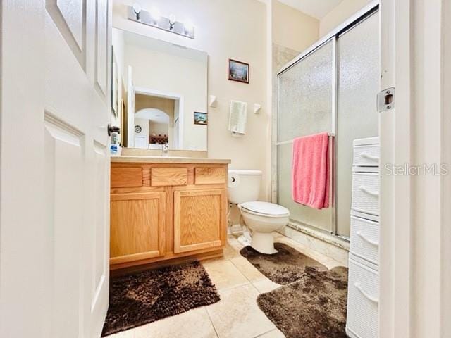 bathroom featuring vanity, tile patterned floors, toilet, and an enclosed shower