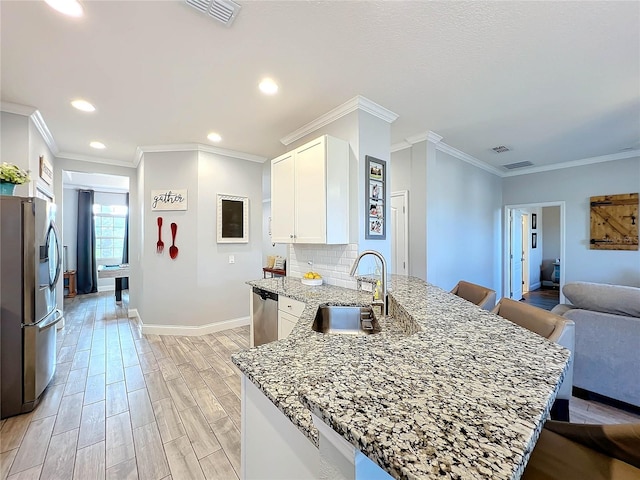 kitchen with light hardwood / wood-style floors, stainless steel appliances, sink, light stone countertops, and white cabinetry