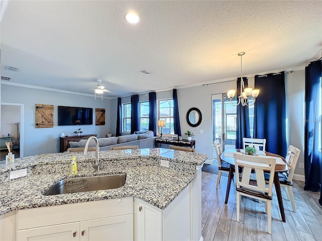 kitchen featuring white cabinets, a textured ceiling, sink, and light wood-type flooring