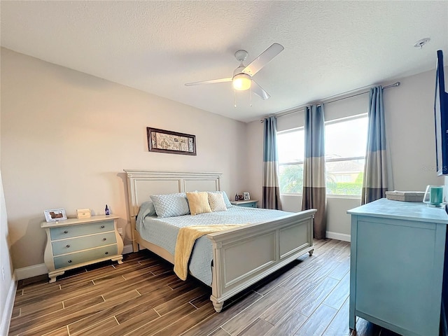 bedroom with ceiling fan, a textured ceiling, and dark hardwood / wood-style flooring