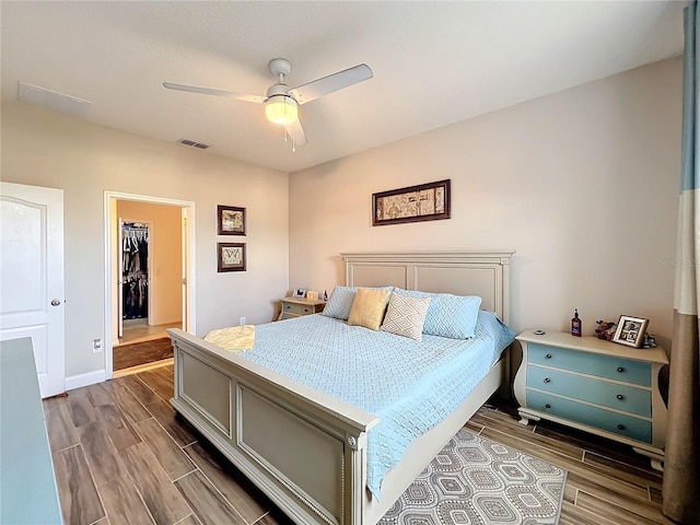 bedroom with hardwood / wood-style flooring, ceiling fan, a closet, and a walk in closet