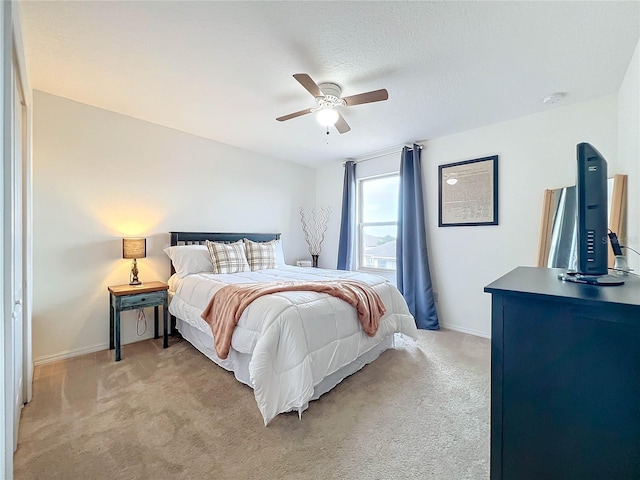 bedroom with a textured ceiling, light carpet, and ceiling fan