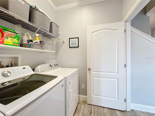 laundry area with washer and clothes dryer, ornamental molding, and light hardwood / wood-style floors