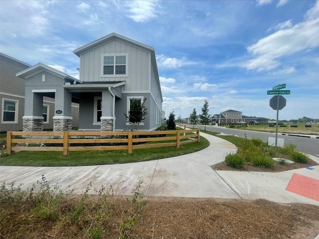 view of front of home with board and batten siding, stucco siding, a fenced front yard, and stone siding