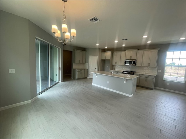 kitchen with a sink, visible vents, stainless steel appliances, baseboards, and an inviting chandelier