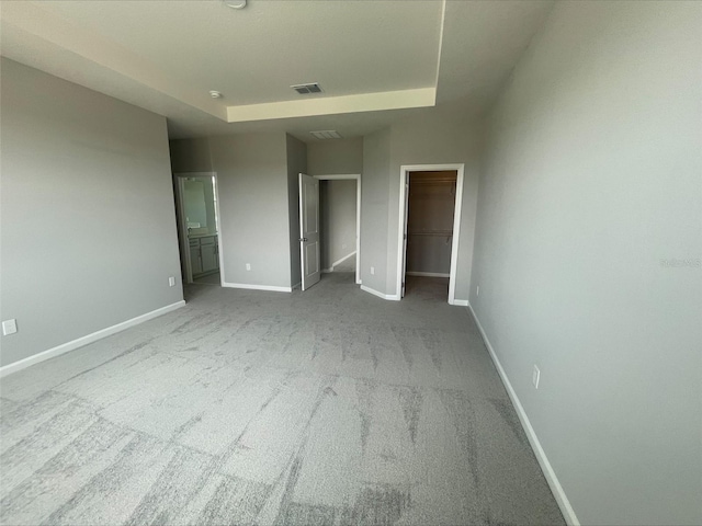 unfurnished bedroom featuring visible vents, a walk in closet, carpet flooring, and baseboards