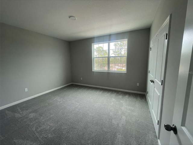 unfurnished bedroom featuring dark colored carpet and baseboards
