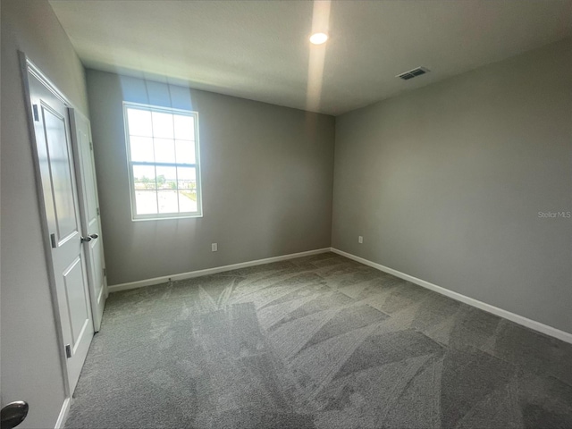 carpeted empty room featuring visible vents and baseboards