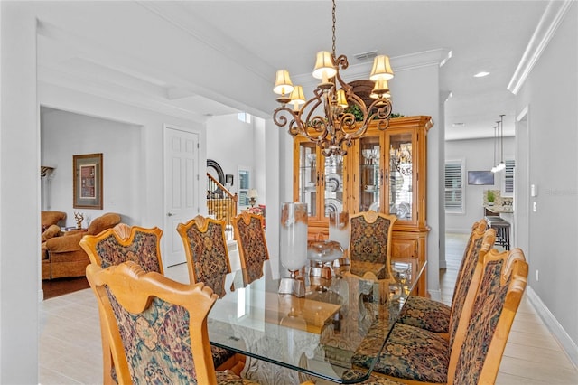 dining area featuring ornamental molding, light hardwood / wood-style flooring, and an inviting chandelier