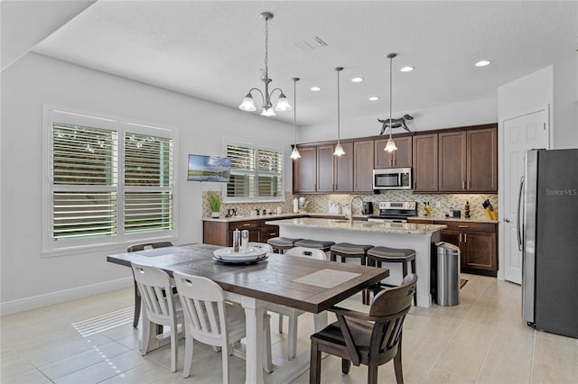 tiled dining area featuring a textured ceiling, plenty of natural light, a notable chandelier, and sink