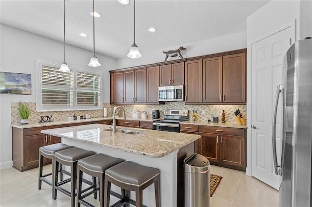 kitchen with decorative backsplash, sink, a kitchen island with sink, and appliances with stainless steel finishes