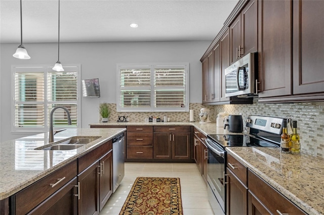 kitchen featuring stainless steel appliances, sink, light stone countertops, hanging light fixtures, and dark brown cabinets