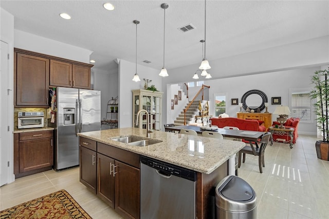 kitchen featuring stainless steel appliances, sink, a textured ceiling, a kitchen island with sink, and pendant lighting