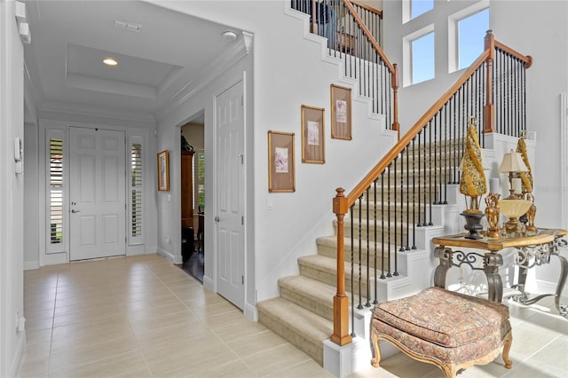 foyer featuring light tile patterned floors and a raised ceiling