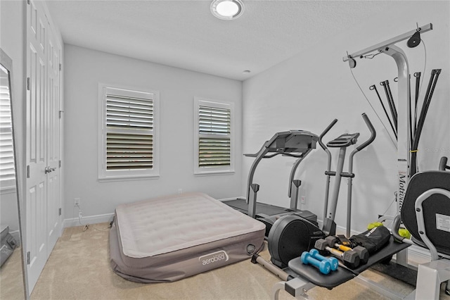 workout area featuring a textured ceiling and light carpet