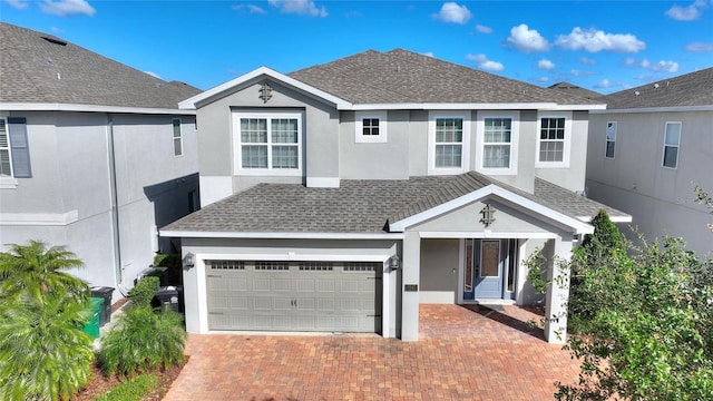 traditional-style home featuring stucco siding, decorative driveway, and roof with shingles