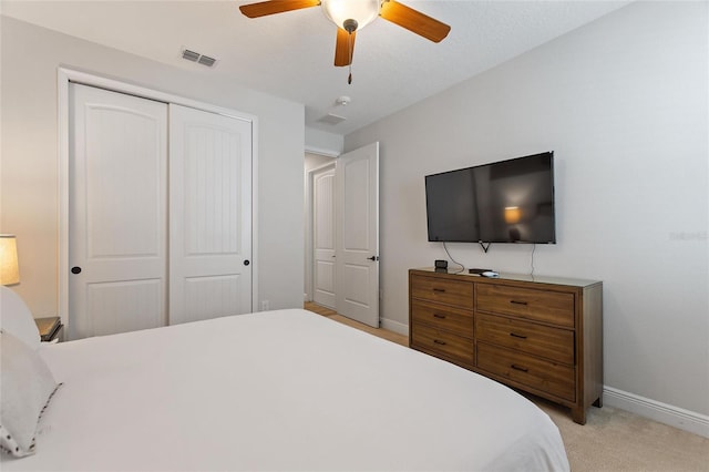 bedroom featuring a closet, light colored carpet, and ceiling fan