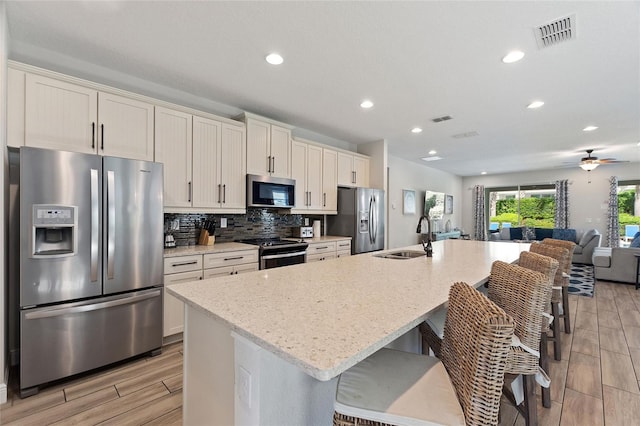 kitchen featuring appliances with stainless steel finishes, sink, an island with sink, and a breakfast bar