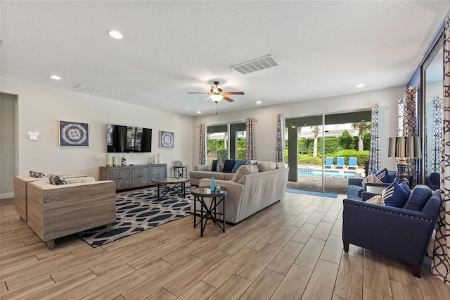 living room featuring ceiling fan, a textured ceiling, and light hardwood / wood-style flooring