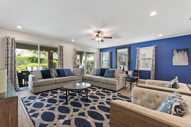 living room with light wood-type flooring, a textured ceiling, and ceiling fan