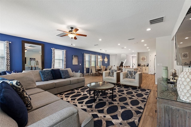 living room featuring sink, a textured ceiling, ceiling fan, and light hardwood / wood-style flooring