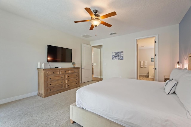 carpeted bedroom with a textured ceiling, ensuite bath, and ceiling fan