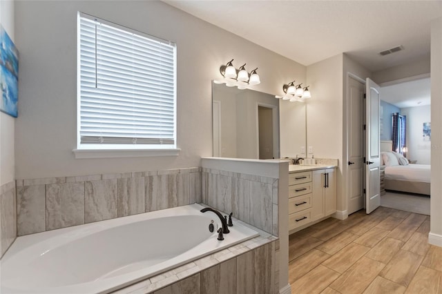 bathroom with vanity and a relaxing tiled tub