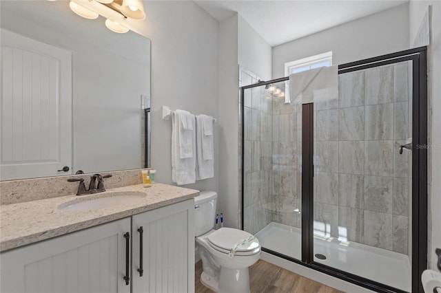 bathroom featuring toilet, vanity, hardwood / wood-style floors, and a shower with door