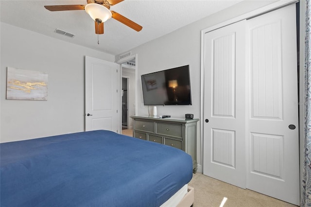 carpeted bedroom featuring a textured ceiling, ceiling fan, and a closet