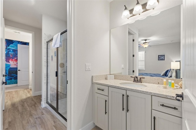 bathroom with walk in shower, ceiling fan, vanity, and hardwood / wood-style flooring